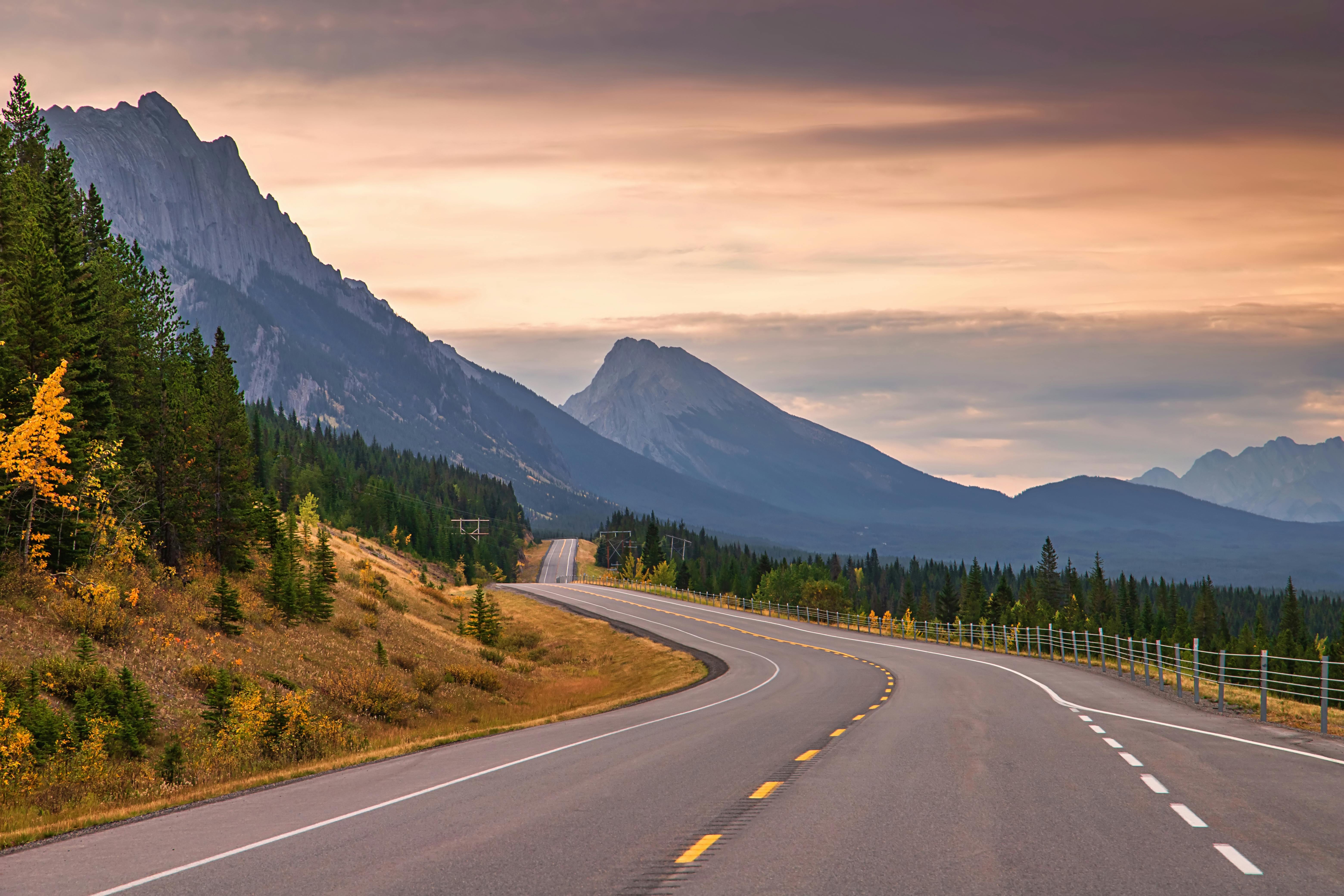 Beautiful sunrise over a mountain road in Kananaskis, Alberta, showcasing stunning landscapes and sky colors.