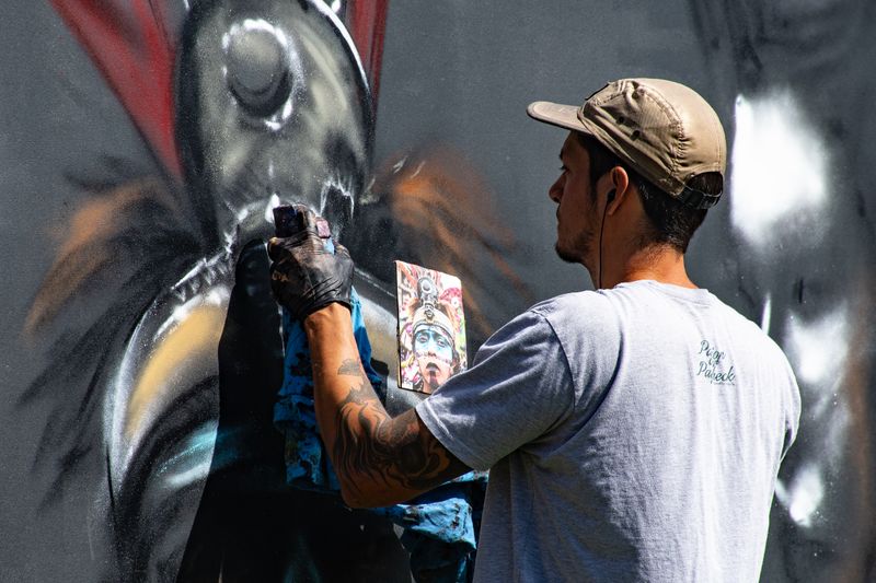 Street artist adding vibrant graffiti to a wall with spray paint