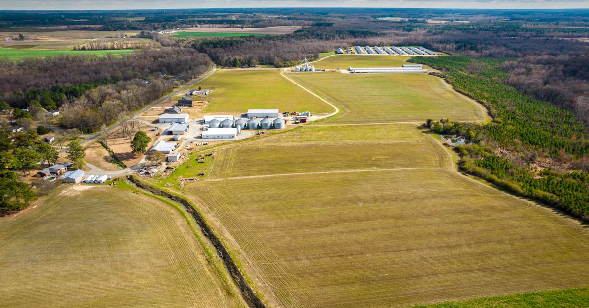 Aerial shot of extensive North Carolina farmlands, showcasing fields and structures.