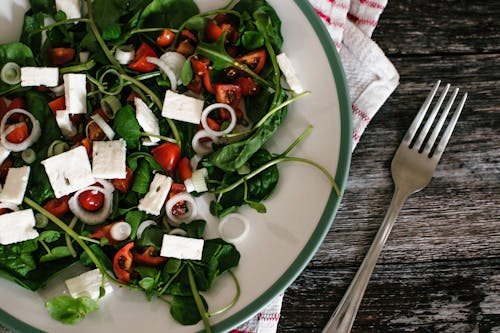 Free 灰色不銹鋼叉旁邊的白色陶瓷板上的蔬菜色拉 Stock Photo