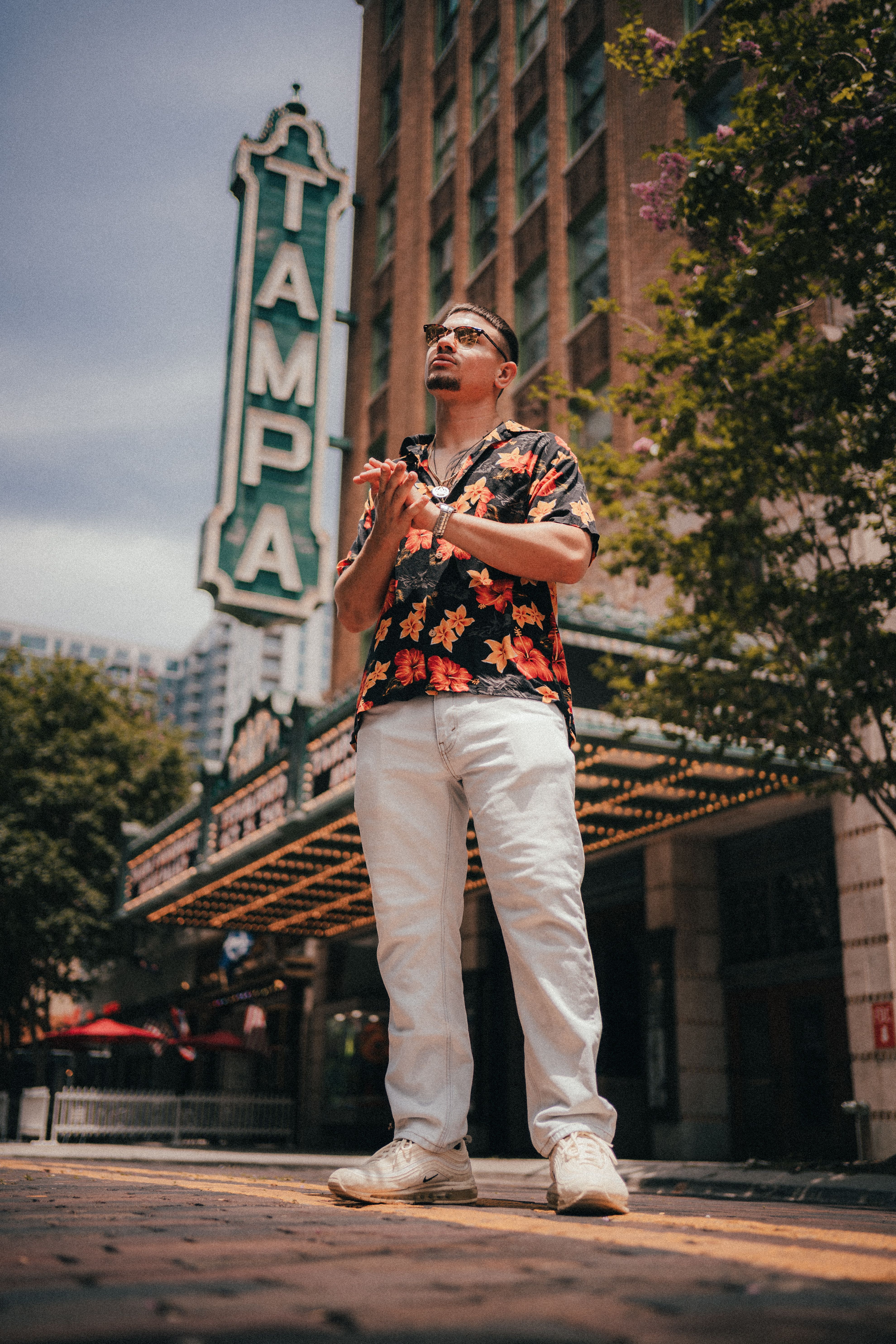 A fashionable man poses confidently in front of the iconic Tampa Theater in sunny Florida.