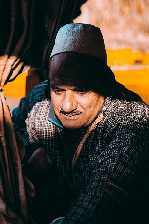 Free Candid image of an older man wearing traditional clothing, highlighted by sunlight. Stock Photo