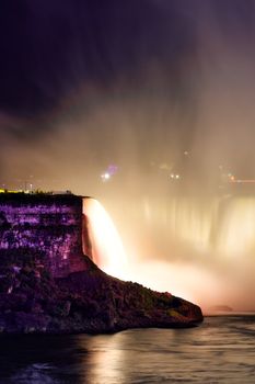 Illuminated Niagara Falls at night with vibrant colors and flowing water, creating a mesmerizing scenic view.