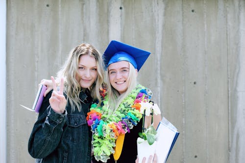 Vrouw Met Blauwe Mortarboard Cap Permanent In De Buurt Van Vrouw Met Blauwe Jas