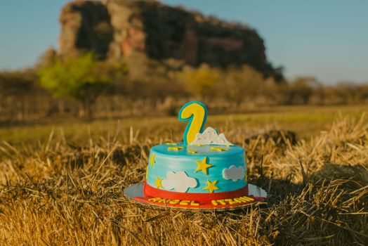Number one birthday cake with blue sky theme on a hay bale, outdoor setting.
