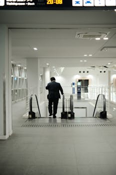 A man in a suit descends an escalator inside a modern airport terminal.