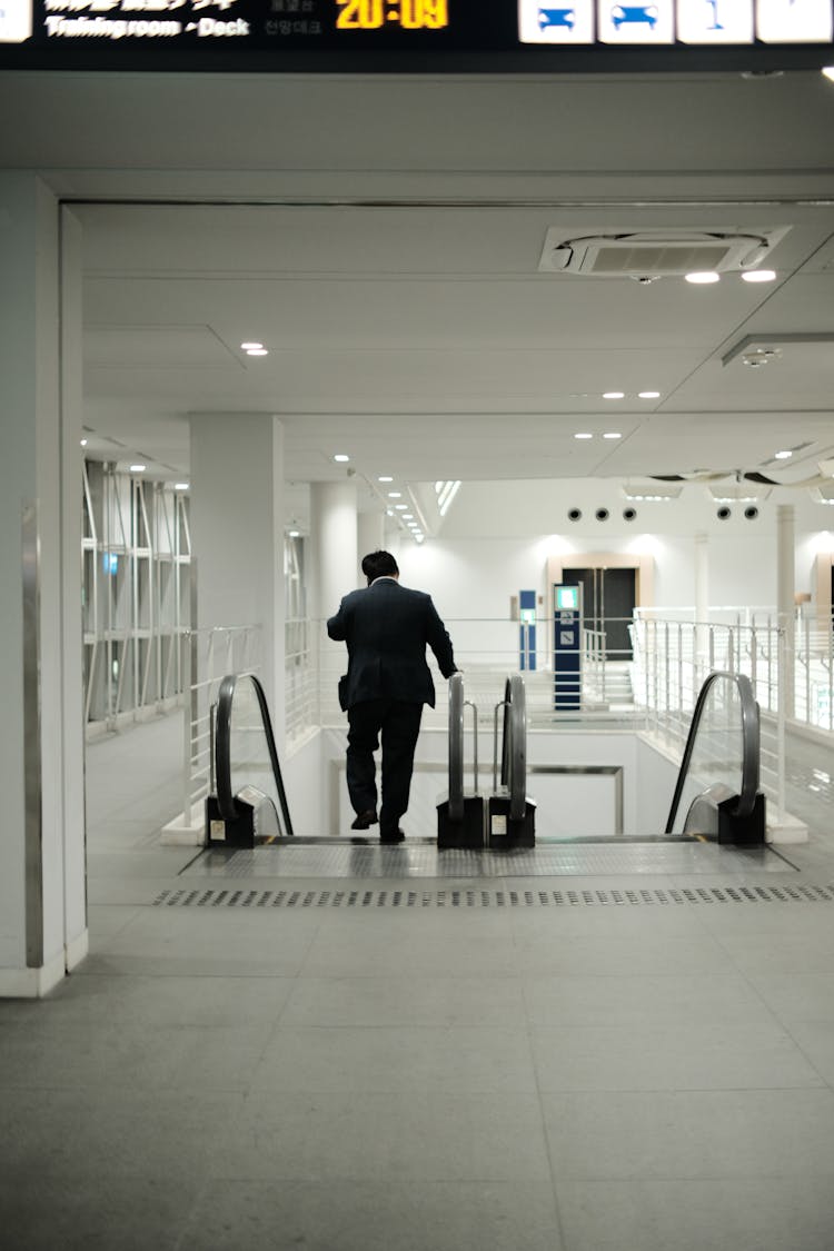 Back View Of A Man Going Down The Escalator