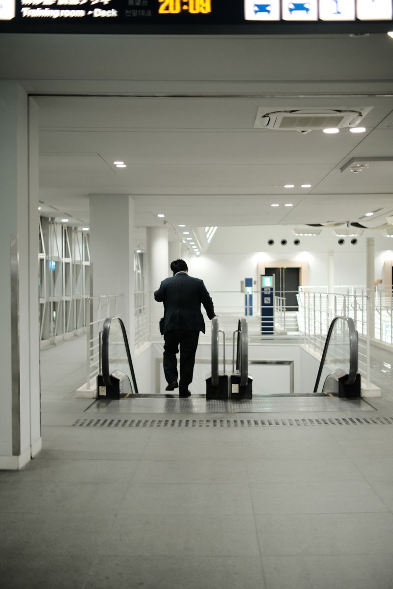 A business traveler in a suit descends an airport escalator