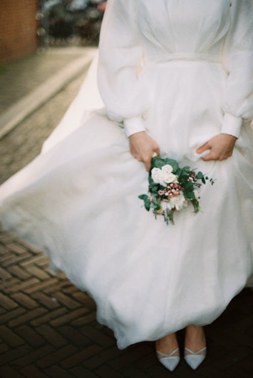 Close-Up Shot of a Woman in White Wedding Gown Holding a Wedding Bouquet