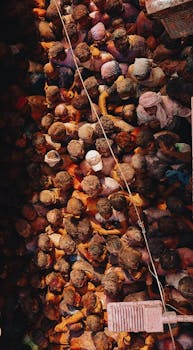 Aerial view of a vibrant crowd celebrating Holi in a narrow street of Vrindavan, India.