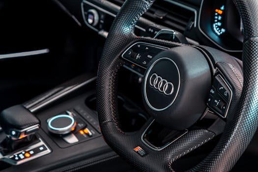 Close-up view of a modern Audi car interior focusing on the steering wheel and dashboard.
