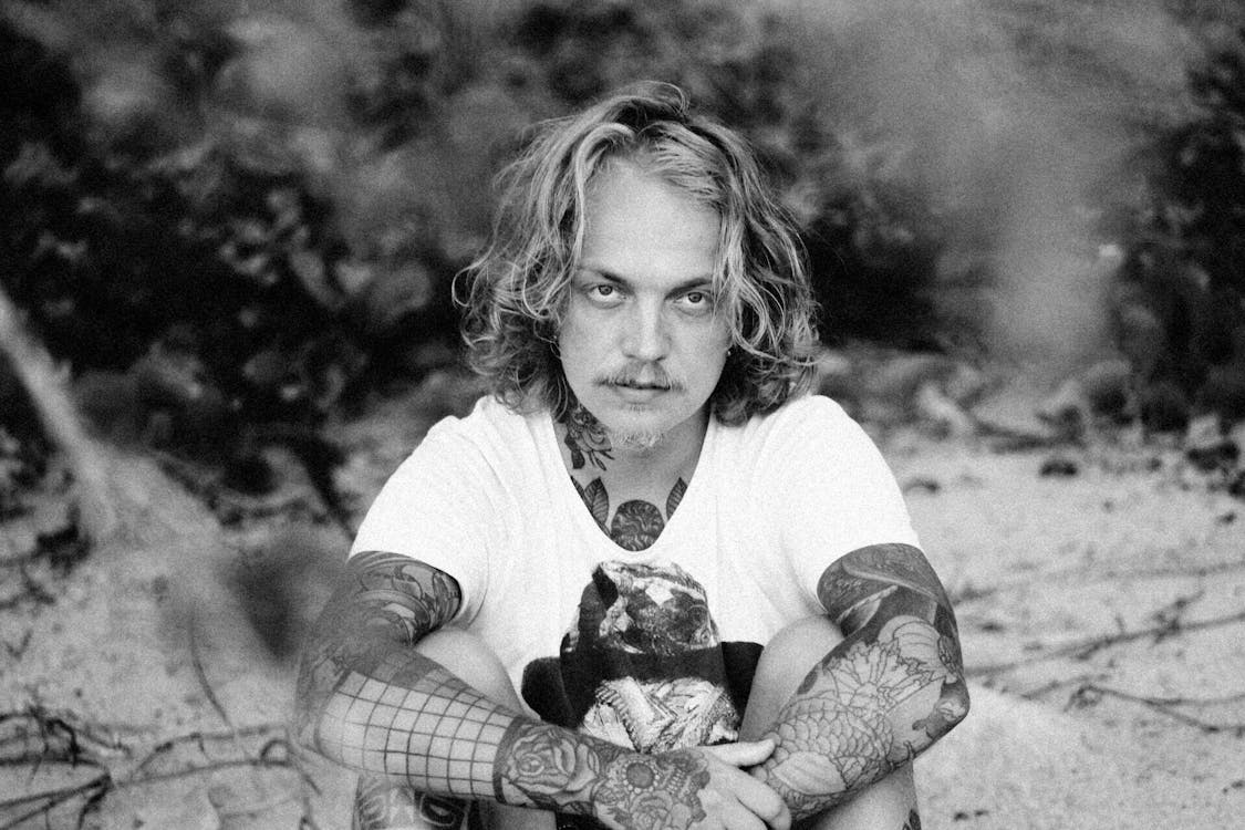 Monochrome Shot of a Tattooed Man with Curly Hair