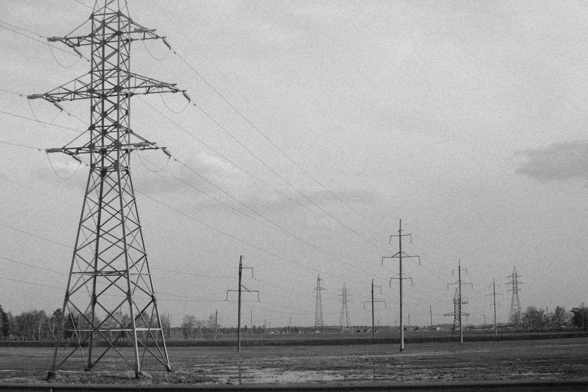 Monochrome image of power transmission towers in a vast field, conveying industrial energy.