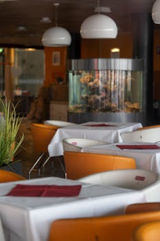 Cozy restaurant interior featuring armchairs, tables, and a unique aquarium centerpiece.