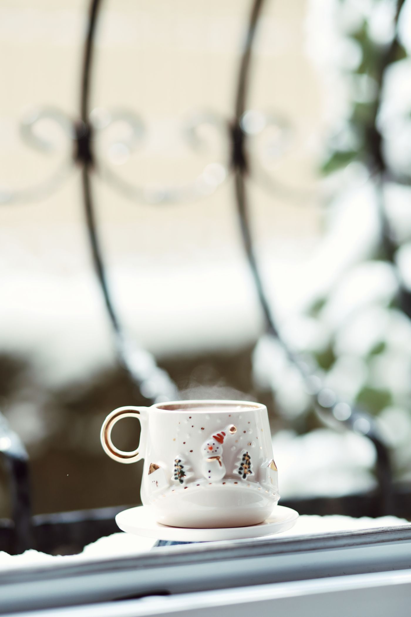 A steaming coffee cup on a snowy window sill on a cold winter morning