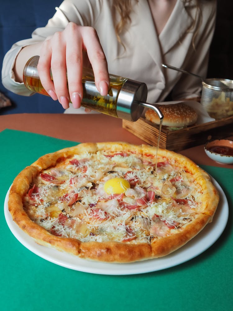 Woman Pouring Oil On Pizza 