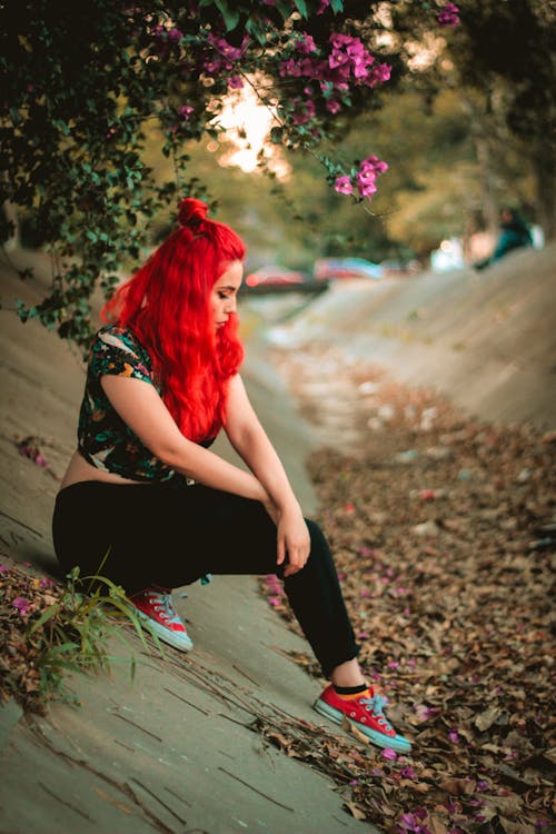 Mujer Vistiendo Crop Top Multicolor De Manga Corta Y Pantalón Negro Sobre Pavimento De Hormigón Bajo Flores De Buganvilla Púrpura