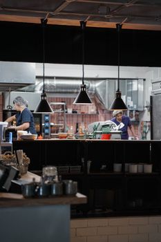 Two women working in a professional kitchen setting focused on food preparation.