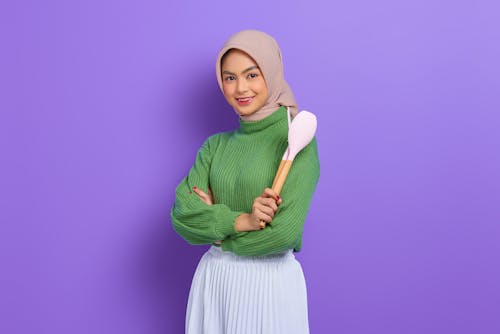 A Woman in Green Sweater and Hijab Holding a Ladle