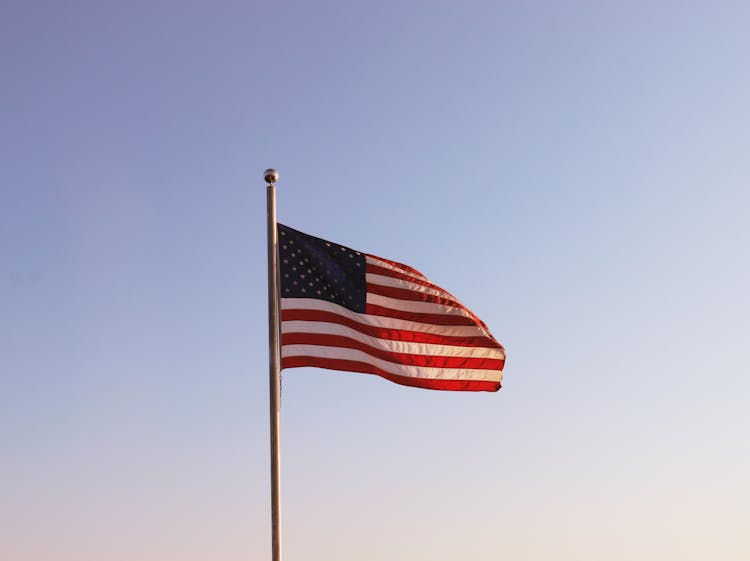 Flag Of The United States On A Mast Against A Clear, Blue Sky 