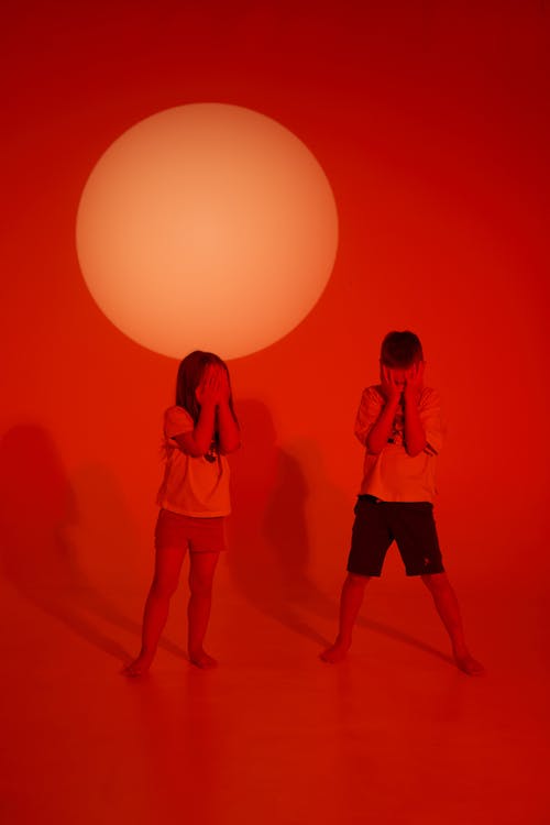 Children Covering Faces on Red Background