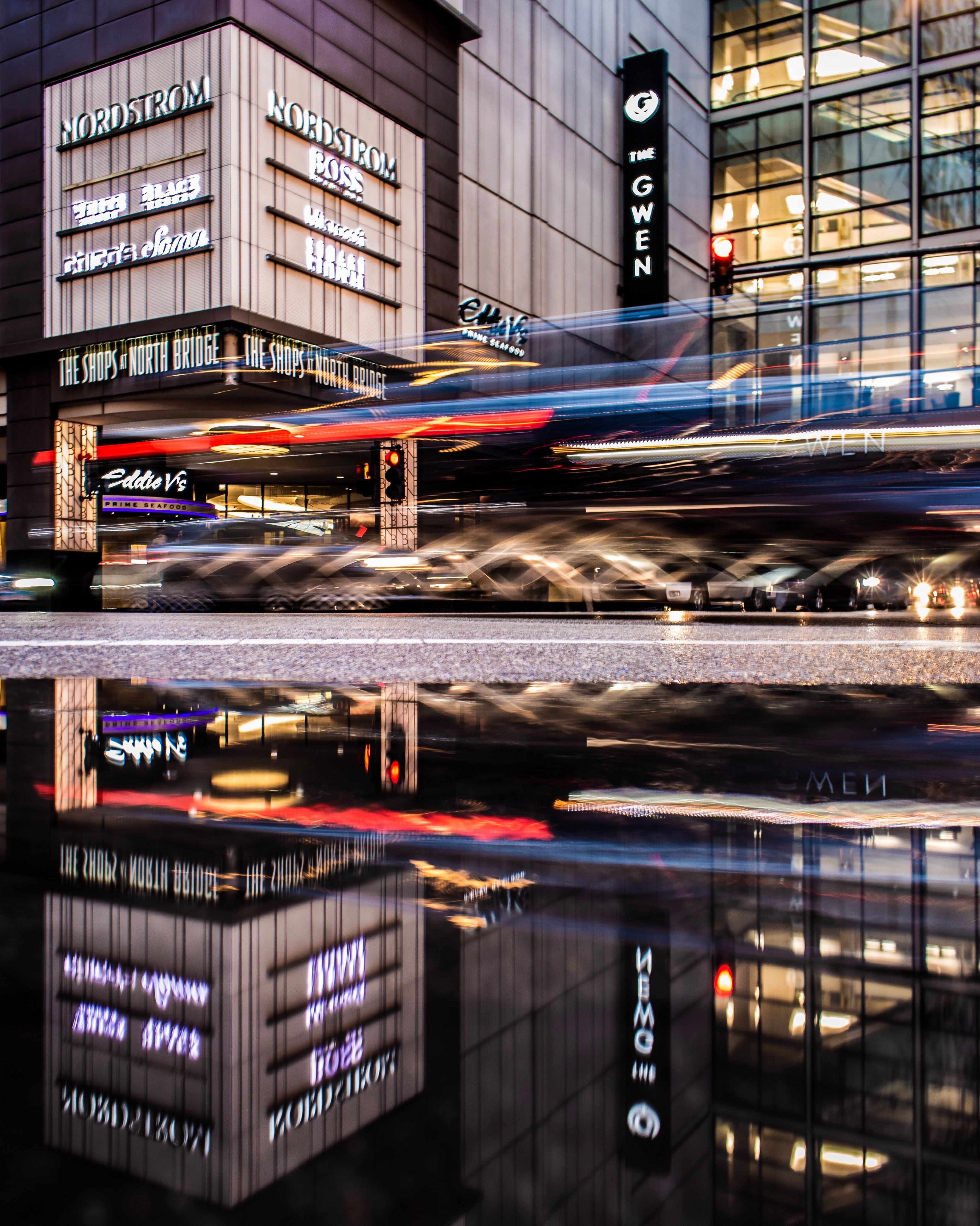 Dynamic night scene on Chicago's Magnificent Mile with light trails and reflections.