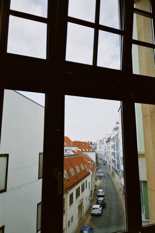 Free Urban street view seen through a large window, showcasing residential buildings and parked cars. Stock Photo
