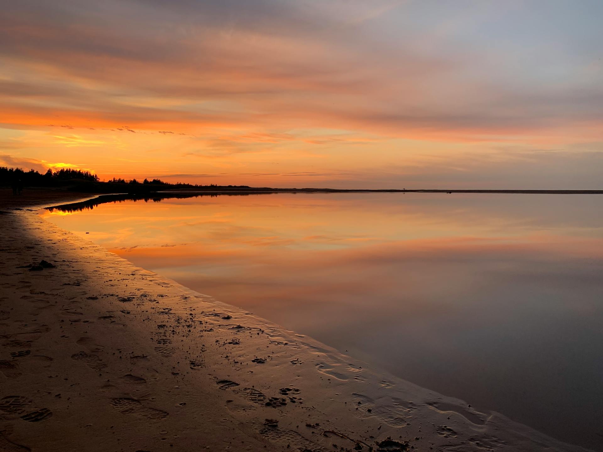 Tranquil sunset reflection on a Prince Edward Island beach, with vivid skies and calm waters.