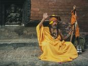 A Man in Yellow Traditional Wear Sitting on Pavement
