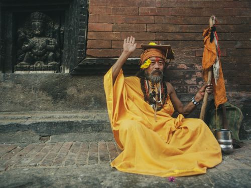 Free A senior monk sits outdoors in traditional yellow attire, exuding cultural depth and serenity. Stock Photo
