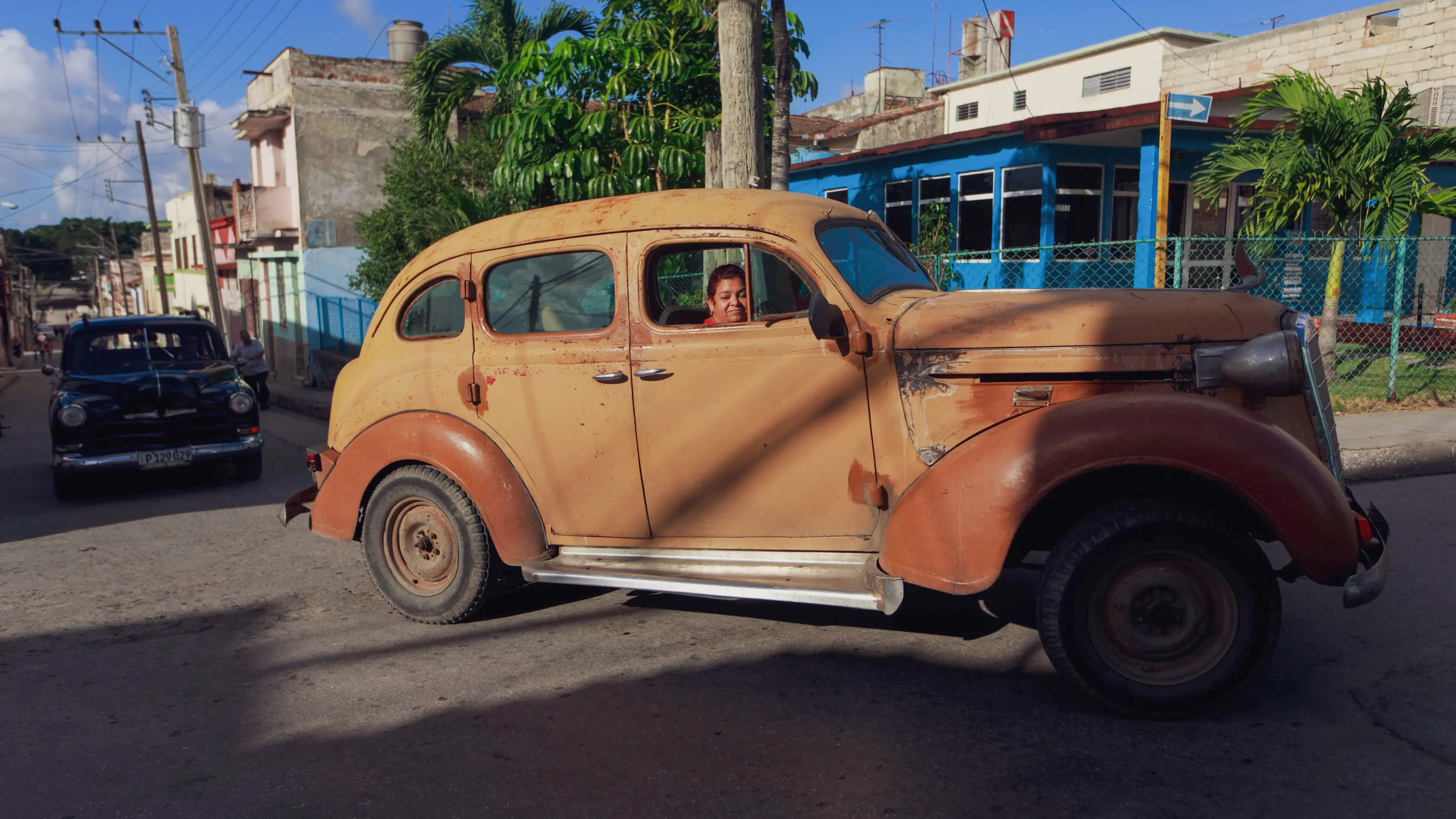 A classic rusty car in a vibrant Cuban street exudes nostalgia and charm.