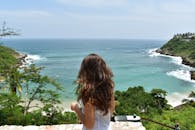 一名女子正在墨西哥瓦哈卡欣赏风景如画的海滩，四周环绕着郁郁葱葱的绿植和充满活力的大海