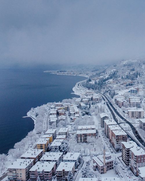 Free Drone view of a coastal city covered in snow, showcasing winter urban beauty. Stock Photo