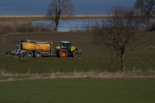 Free Claas tractor on meadow delivering manure Stock Photo
