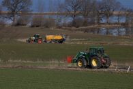 John Deere tractor driving towards stuck Claas tractor on meadow