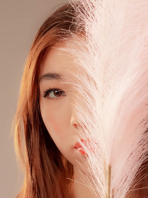 Free A Woman's Face Partially Covered with White Feathers Stock Photo