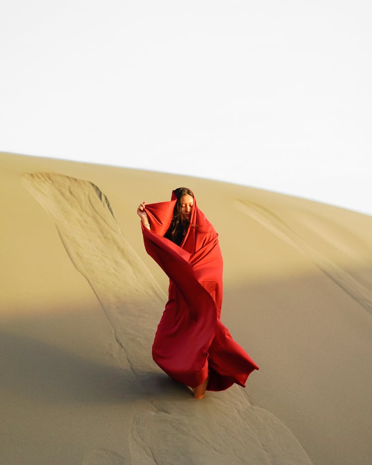 Woman Wrapped In Red Fabric Standing In Desert Sand