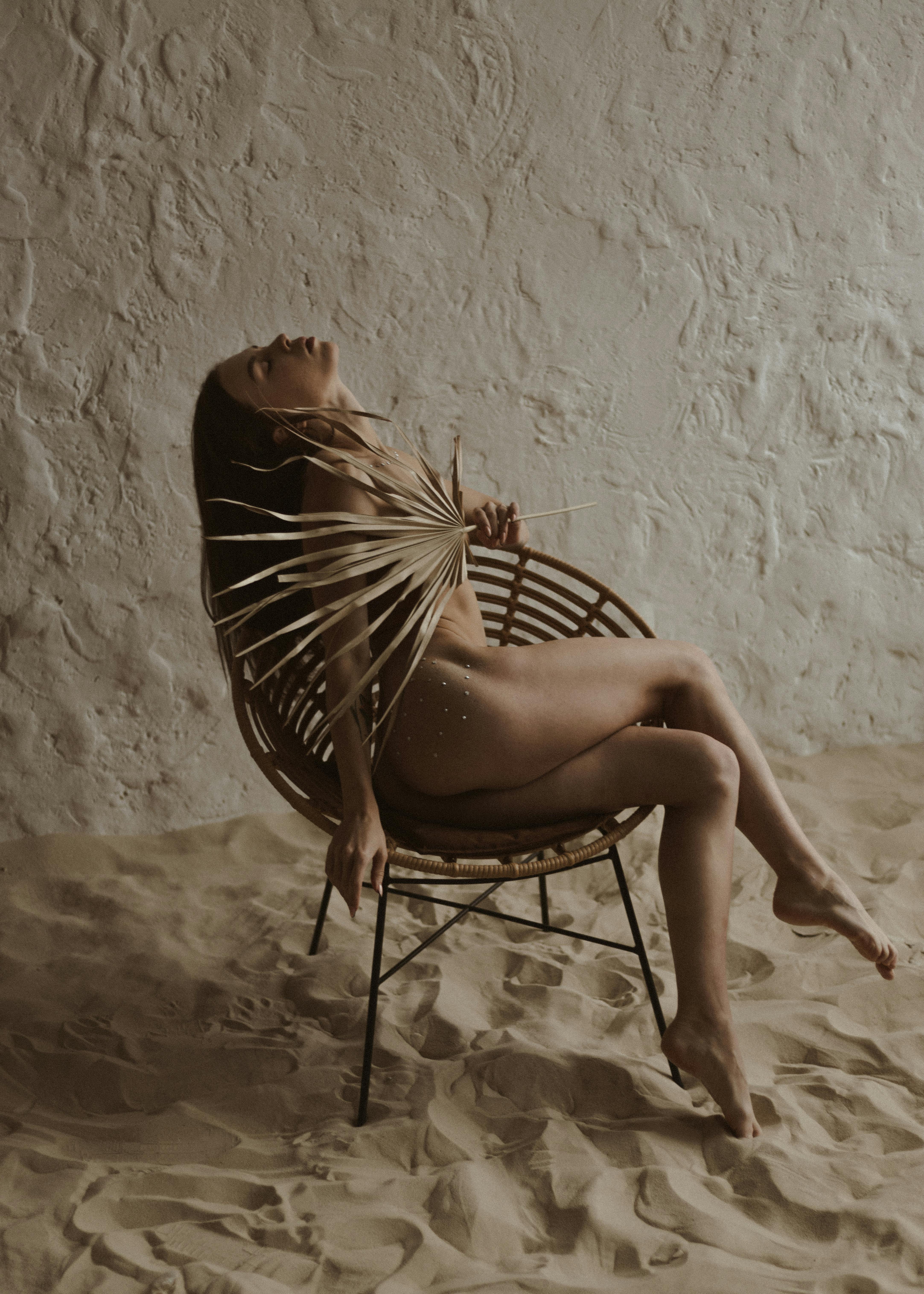 a nude woman sitting on a chair