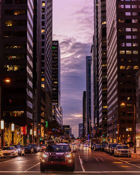 Vibrant street view of Philadelphia's illuminated cityscape at dusk, featuring modern high-rises and lively city lights.