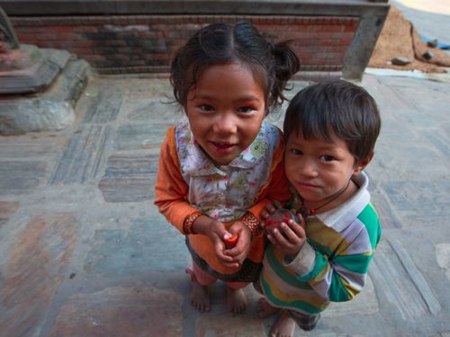 Free Two cute Asian children standing barefoot outdoors, smiling brightly. Stock Photo