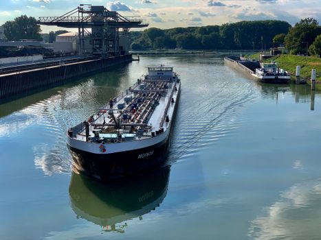 A cargo ship navigates through industrial harbor waters in Karlsruhe, Germany.