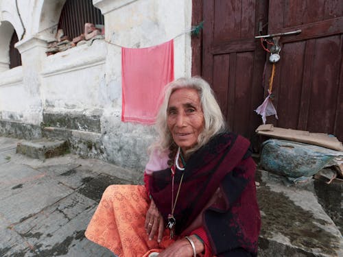 Free An Elderly Woman Sitting Near a Dooor Stock Photo