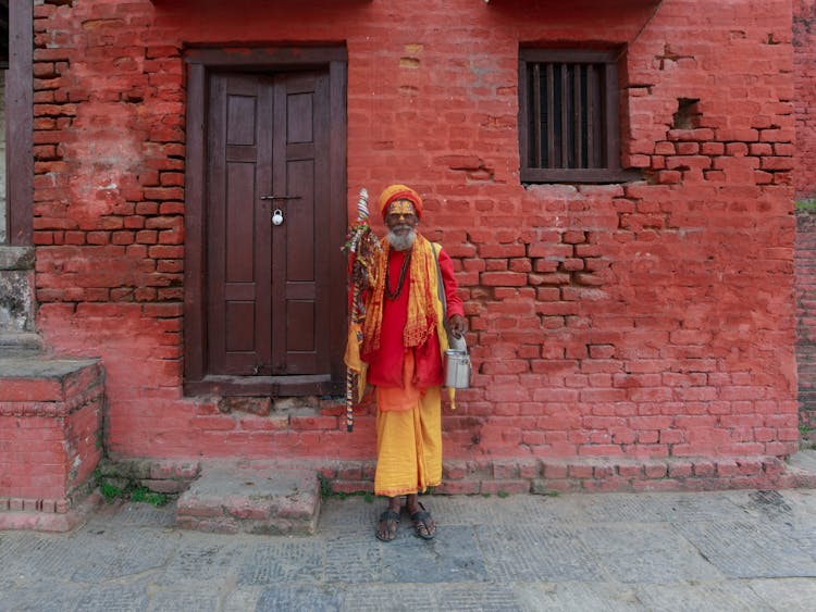 A Man In Traditional Clothes Standing Outside Of A House