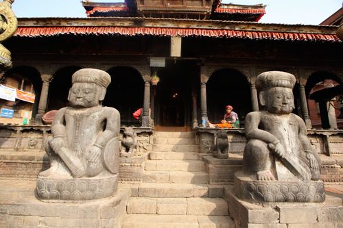 Free Two ancient stone statues guard the entrance to a historical temple with intricate architecture. Stock Photo