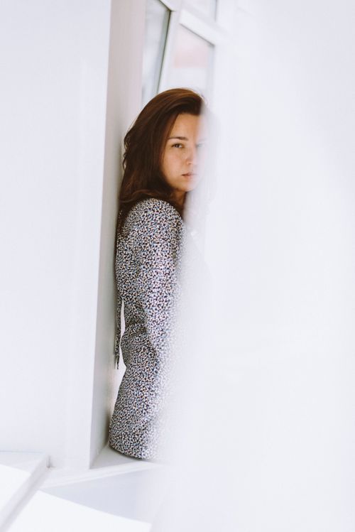 Free Artistic portrait of a woman leaning in a bright, minimalist space with natural light. Stock Photo