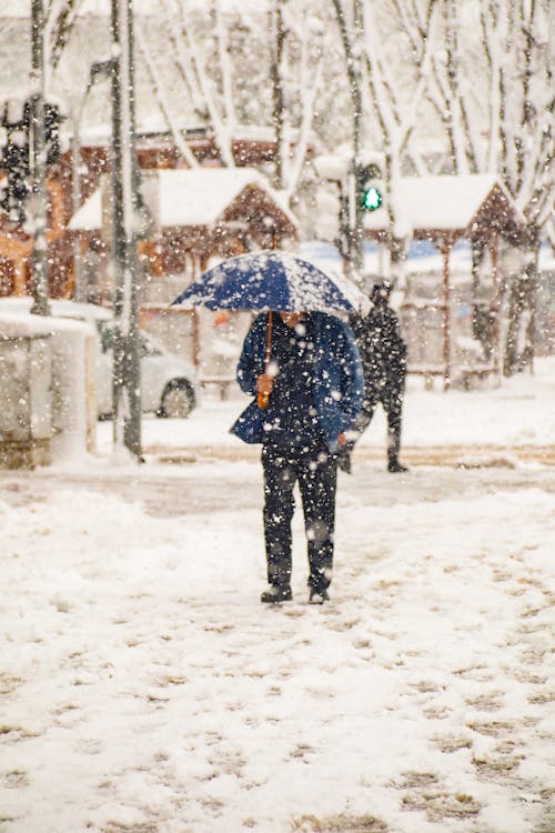 A Man Using an Umbrella during a Snowy Day