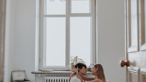 Couple embracing on a cozy bed by a large window with natural light in a modern bedroom.
