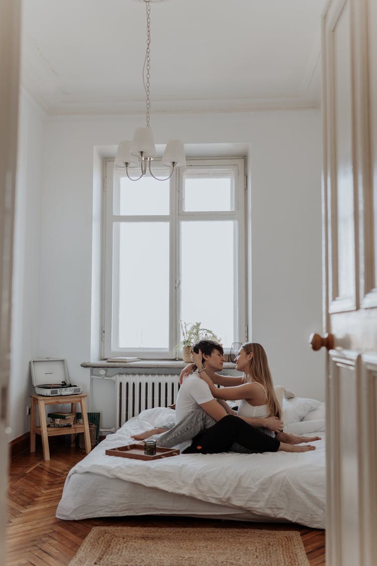 Couple Embracing While Sitting On Bed