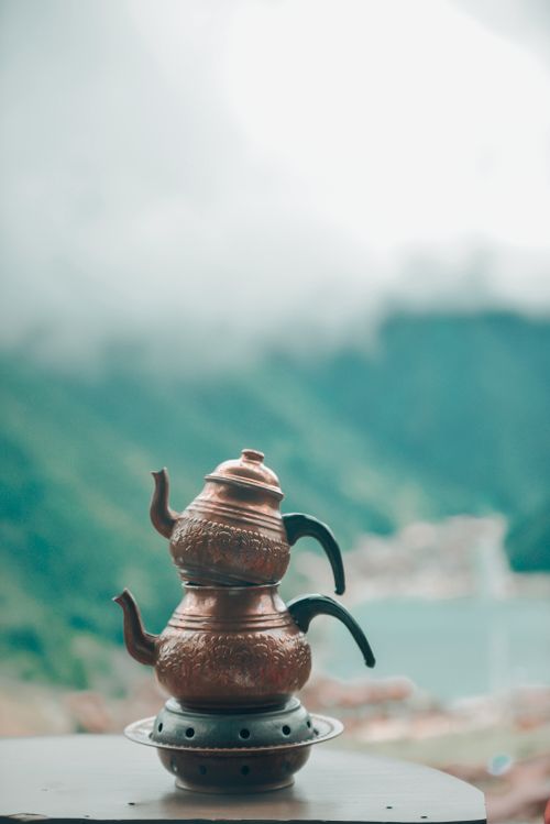 Free A pair of stacked copper teapots set against a misty mountain landscape, capturing serenity. Stock Photo