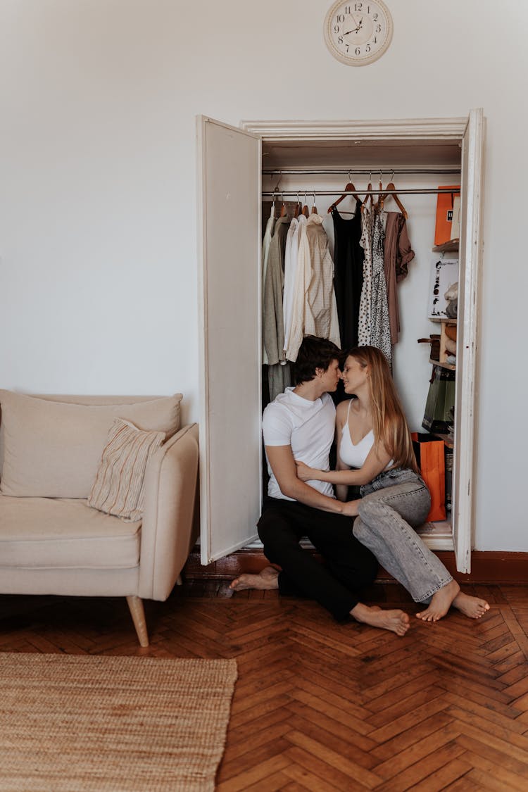 A Couple Kissing While Sitting In A Closet With Open Doors